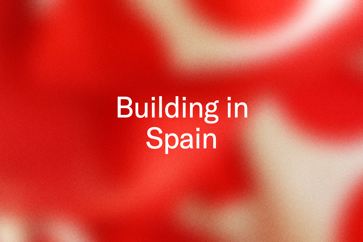 White text "Building in Spain" on a blurred, grainy red and cream background