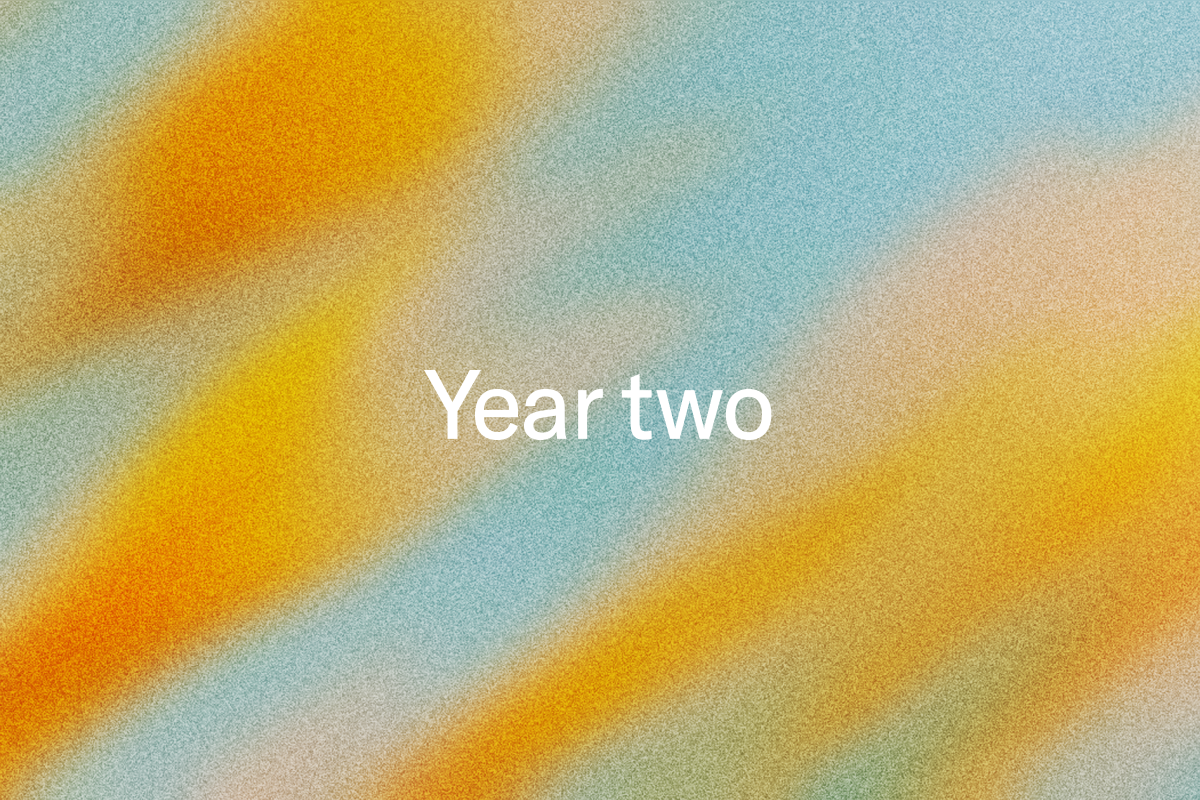 White text "Year two" on a grainy background with diagonal orange, yellow, and blue color gradients.
