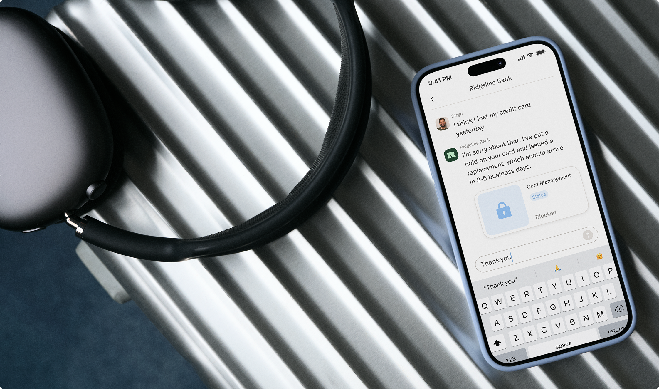 A pair of headphones is on a suitcase next to a iphone, which shows a conversation between a customer and his bank.