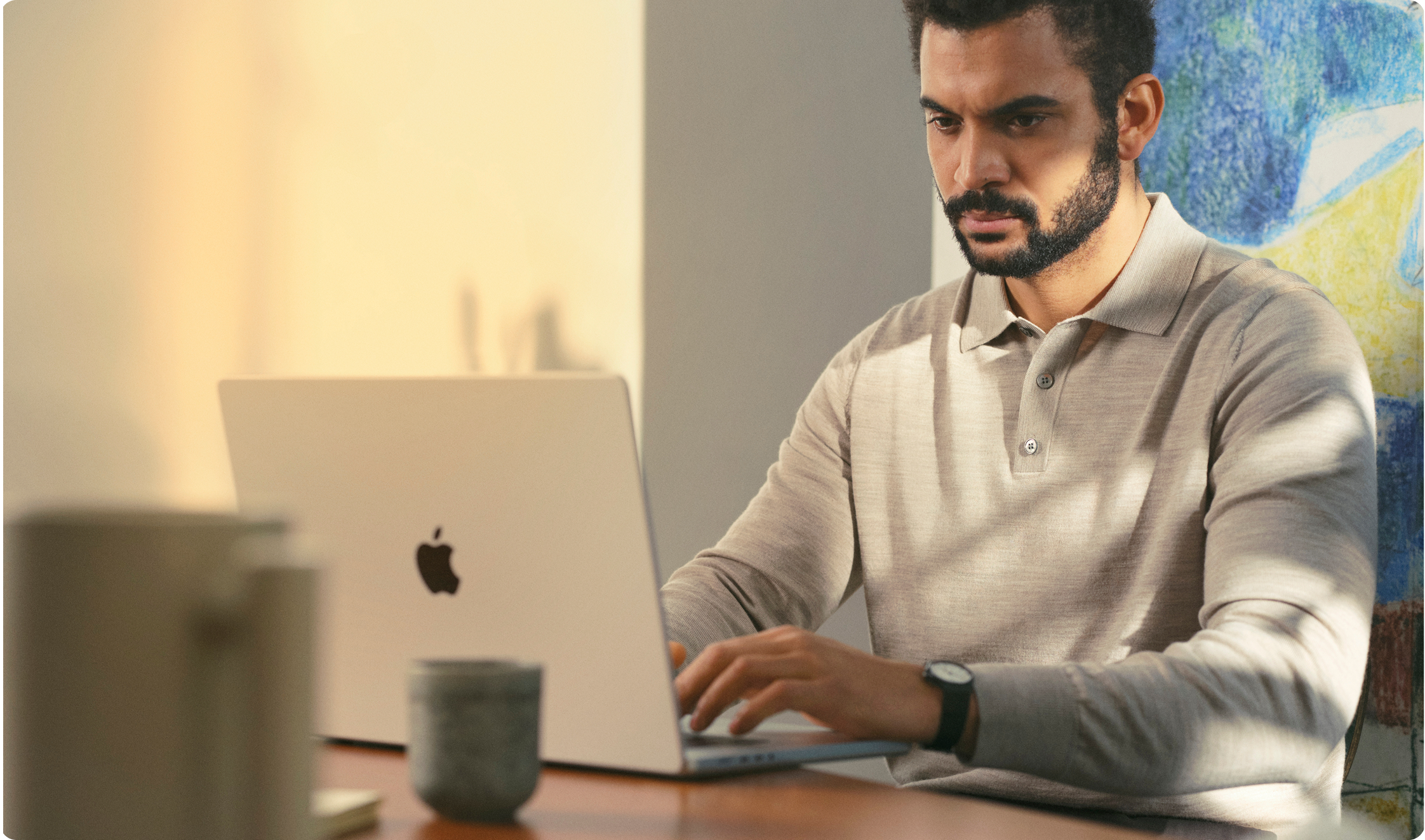 A man sits at a table and types on his computer.